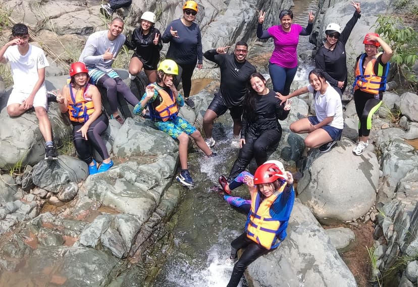 Madres e hijos sonriendo sentados en unas rocas sobre el río