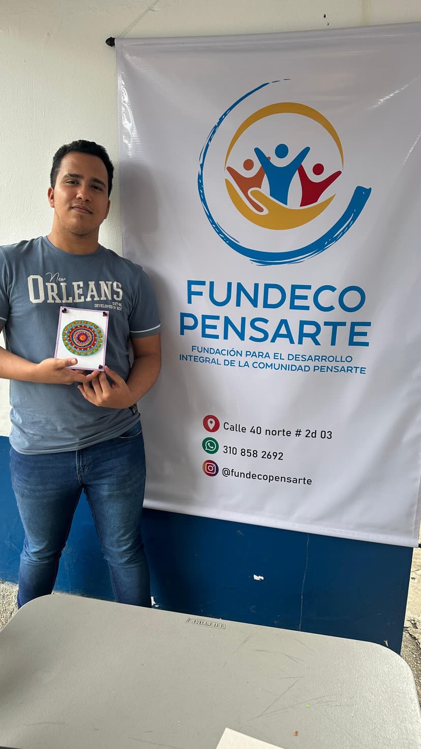 Adulto joven mostrando manualidad con filigrana frente a un pendón de Fundeco pensarte