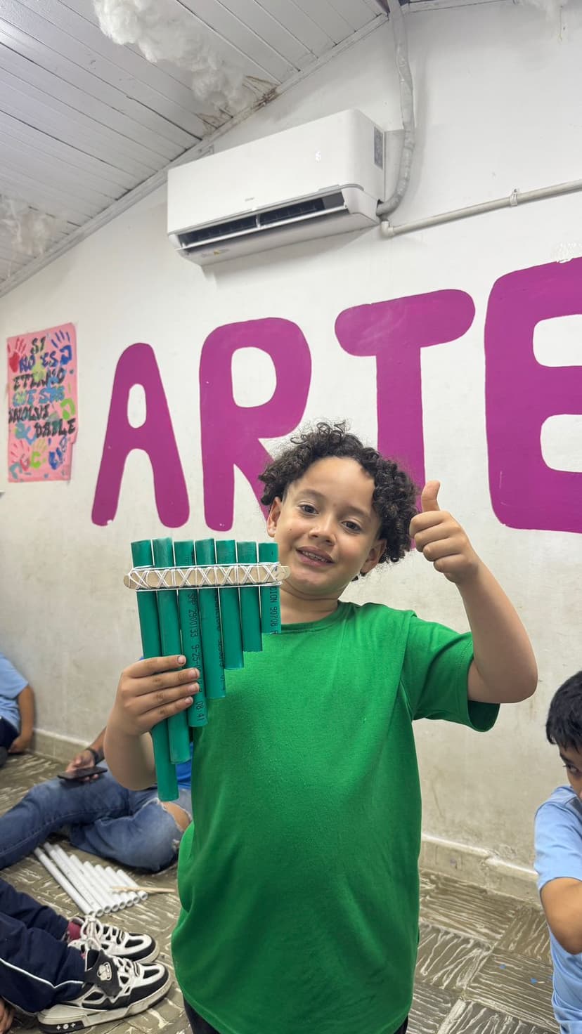 Niño exhibiendo flauta con hecha con objetos reciclables