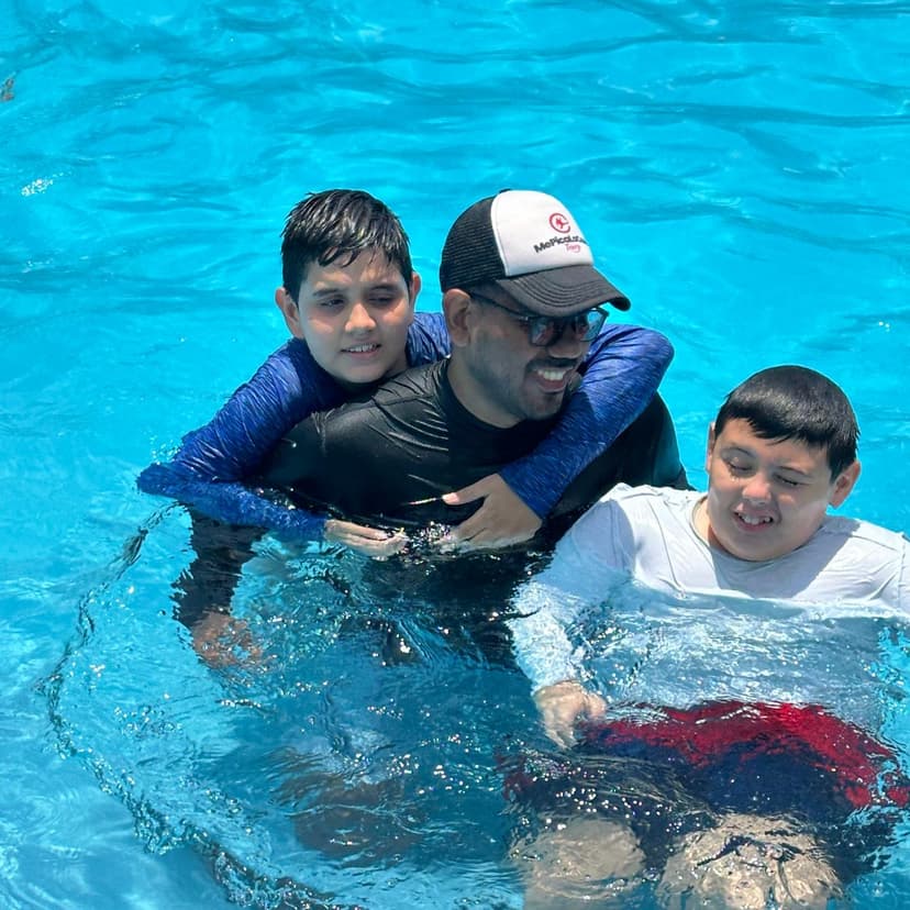 Hombre sonriendo con dos niños en piscina